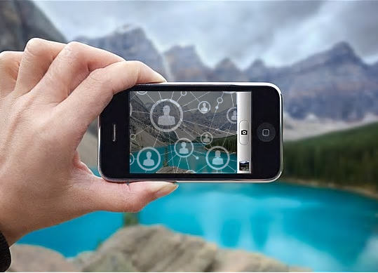 En la foto un móvil tomando una foto de un lago en lo alto de una montaña para compartirla posteriormente con redes sociales