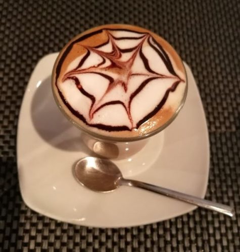 En la foto un café cortado con una telaraña dibujada con chocolate