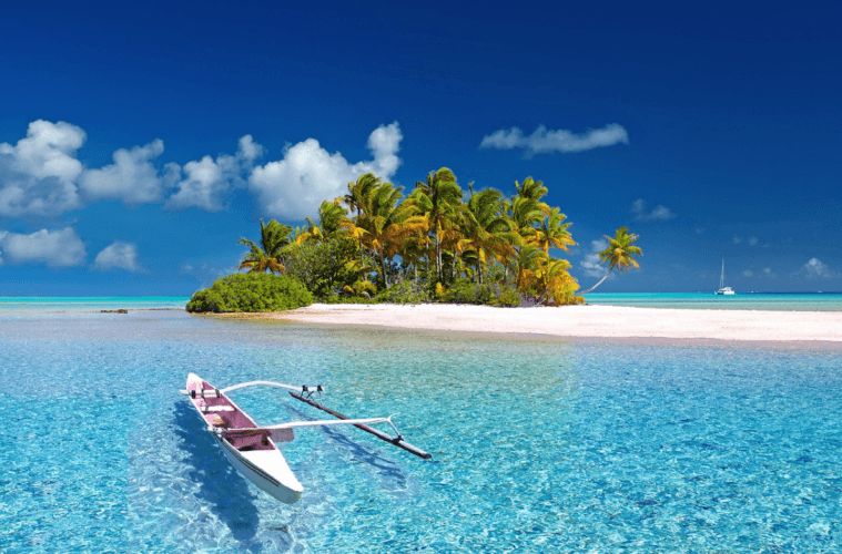 Espectacular foto de una pequeña isla con palmeras, mar turquesa y una pequeña barca en primer plano