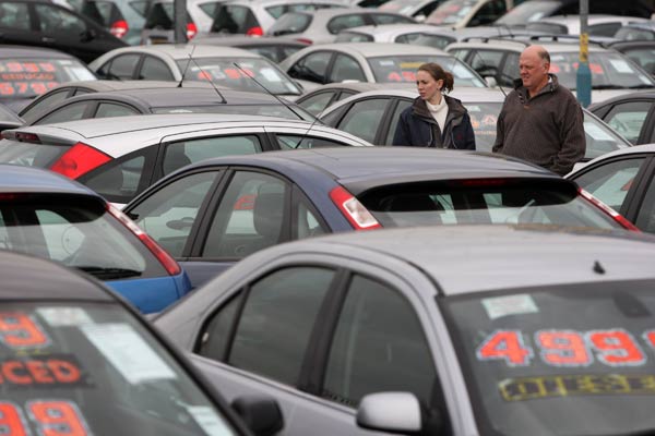 En la foto se ven dos clientes mirando coches de segunda mano en un punto de venta de coches de segunda mano