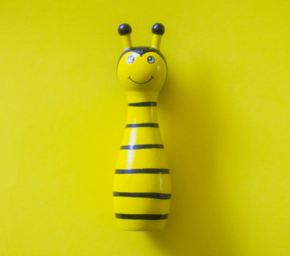 Abeja de juguete de color amarilla sobre un fondo amarillo