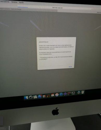 En la foto la pantalla de un iMac mostrando en pantalla un mensaje procedente de un virus informático