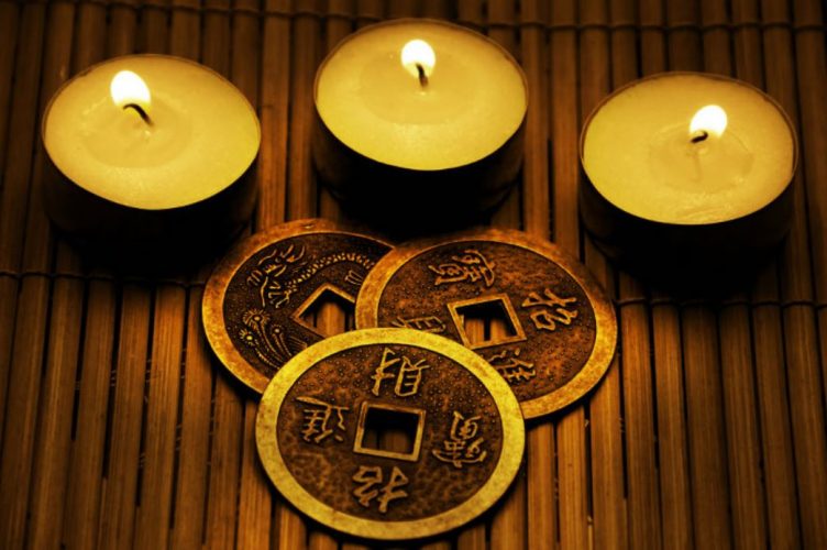 Imagen con las tres monedas del I Ching y tres velitas encendidas sobre una base de madera
