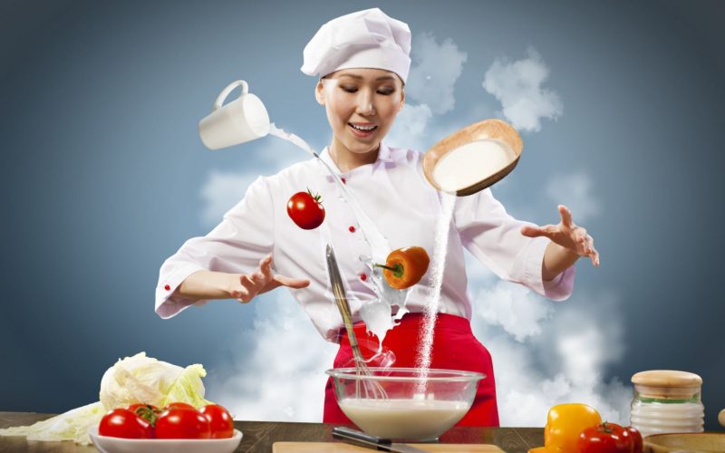 Imagen una cocinera joven con varios ingredientes de alimentos como si volaran por el aire.