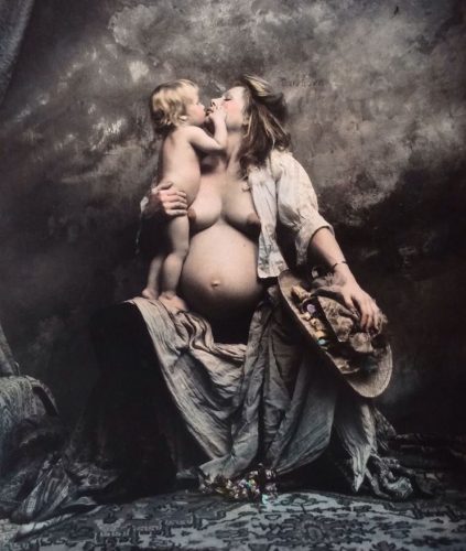 Foto artística de una madre con su hijo. Ambos aparecen semidesnudos, la madre tiene sujeto a su hijo con el brazo derecho mientras le besa.