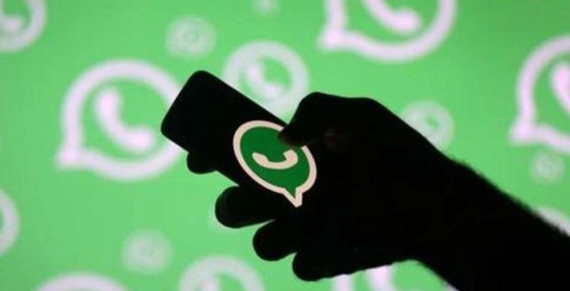 Imagen de mano y móvil con el símbolo de WhatsApp