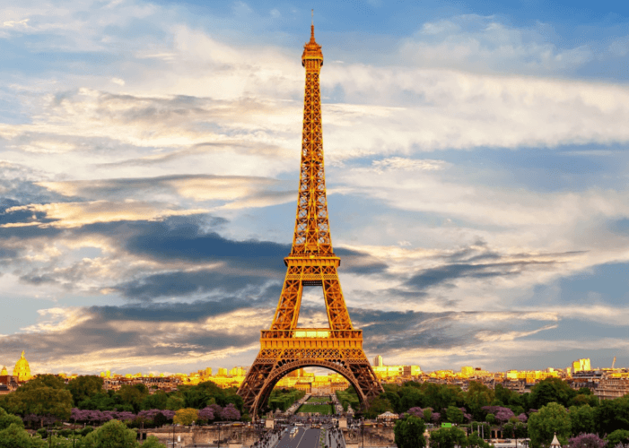 Foto de la Torre Eiffel sobre un cielo azul con nubes blancas, luz de atardecer