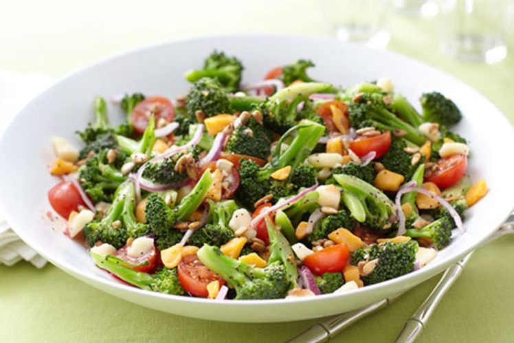 En la foto una apetitosa ensalada en un plato blanco compuesta por brocoli, tomate, cebolla y otros vegetales