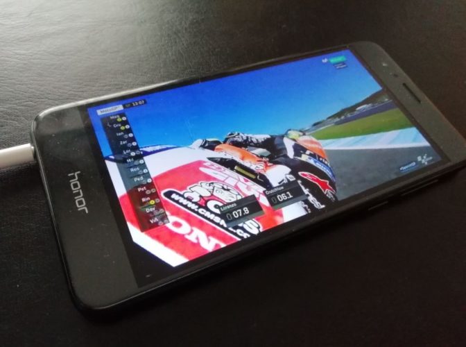 Una foto de un teléfono móvil de la marca Honor reproduciendo las carreras de MotoGP donde se ve a Marc Márquez en primer plano trasero tumbando en una curva