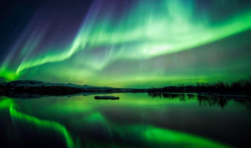 Aurora boreal reflejada en un lago. Foto espectacular con fondos azules y verdes. 