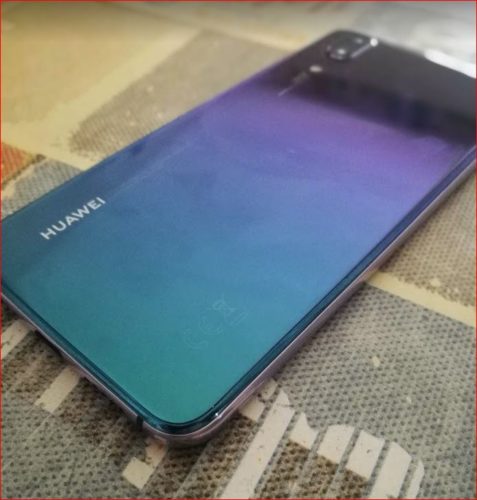En la foto el Huawei P20 boca abajo mostrando su bonita trasera en un color indefinido entre el verde el azul, el violeta y el púrpura