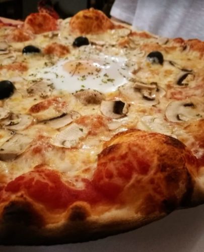 Una foto de una pizza de champiñones olivas negras y huevo frito