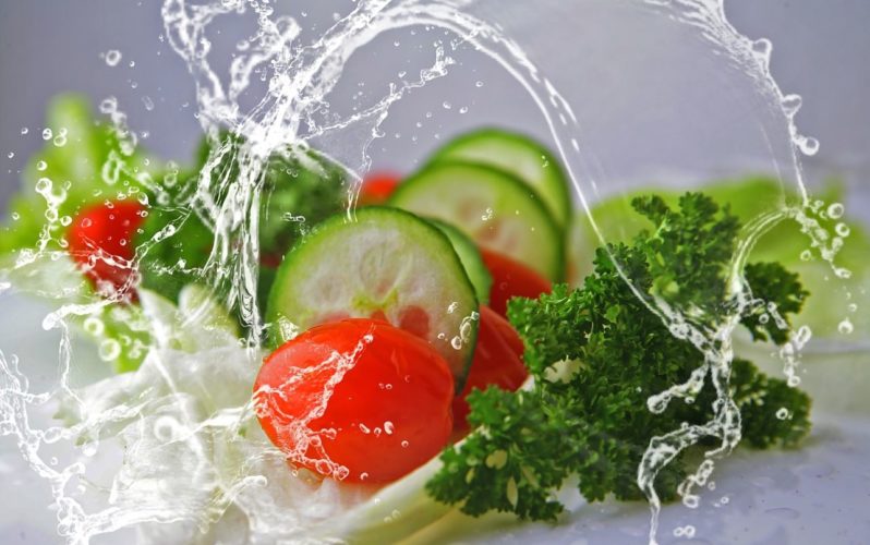 Una refrescante foto con productos vegetales cortados con una ola de agua en medio
