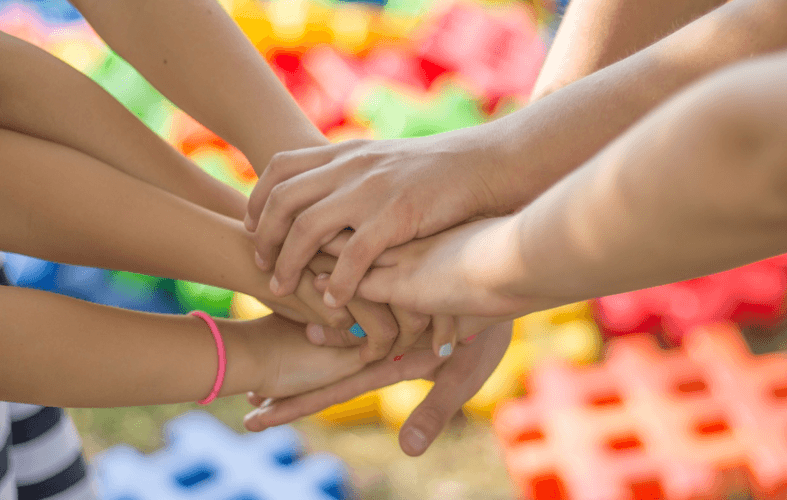 Imagen de muchas manos de niñas unidas en un acuerdo grupal