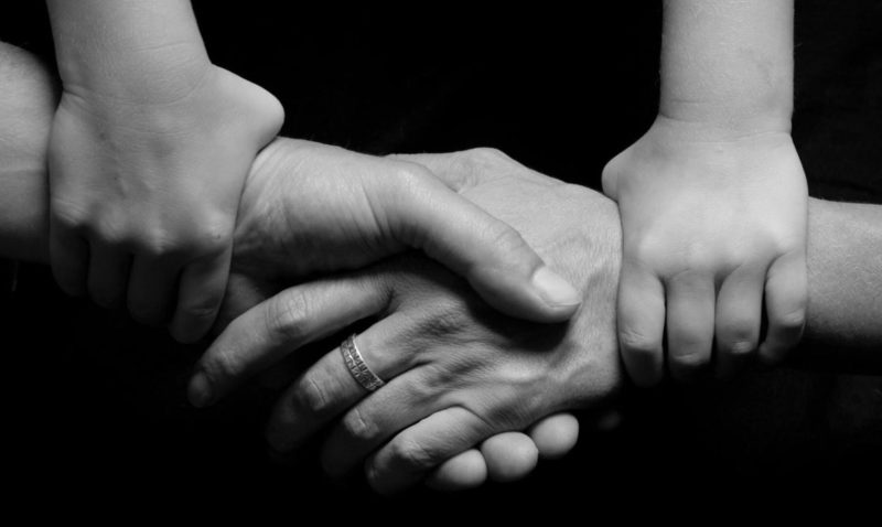 Imagen en blanco y negro donde aparecen cuatro manos unidas en un acuerdo