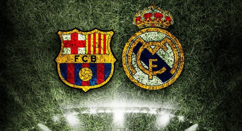 En la imagen sobre el césped de un campo de fútbol los escudo del Barça y del Real Madrid