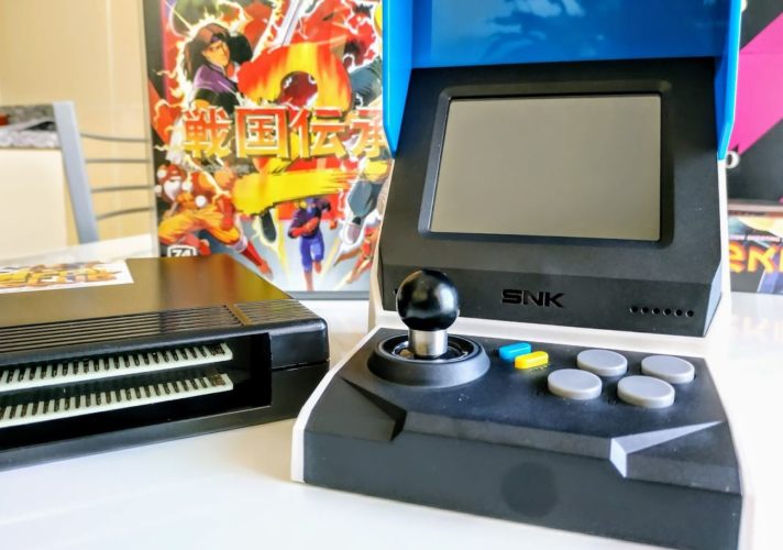 En la foto se muestra la Neo-Geo Mini comparada con un cartucho original de la Neo-Geo primigenia