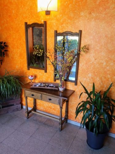 La entrada del restaurante Coll de Condreu es acogedora, con una bonita pared naranja y muebles rústicos