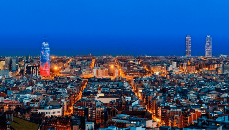 Panorámica nocturna de la ciudad de Barcelona iluminada con el mar de fondo