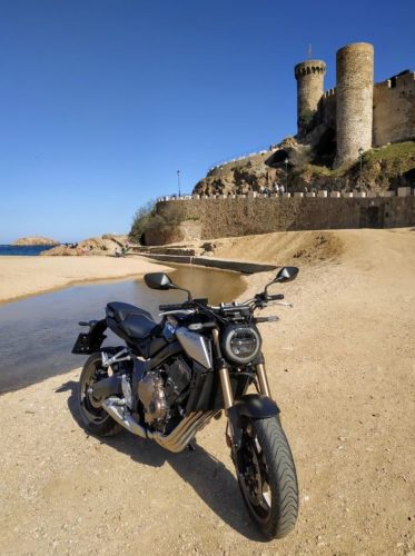 En la foto, la moto Honda CB650R con el castillo de Tossa de Mar al fondo