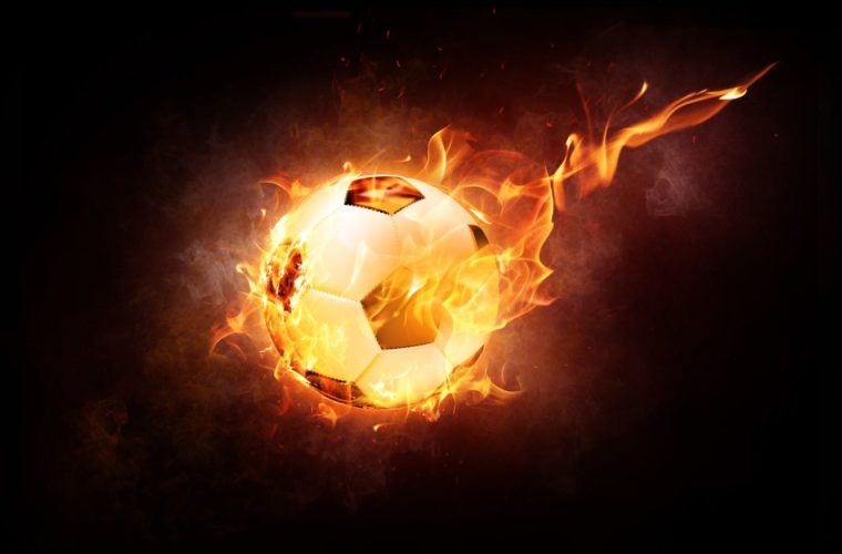En la foto un balón de fútbol envuelto en llamas de fuego
