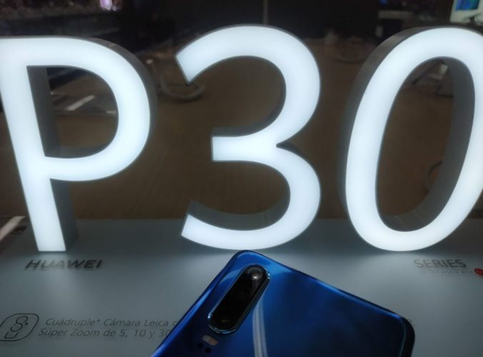 Una foto con el distintivo P30 iluminado y la parte superior del teléfono Huawei P30 colocado bocabajo