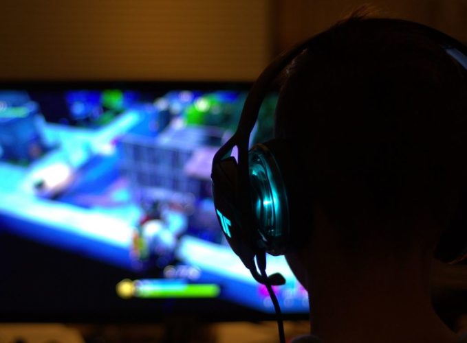 En la foto se observa a un gamer jugando con su PC con los auriculares puestos