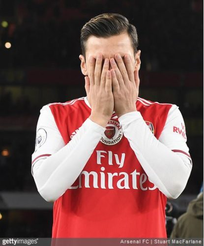 En la foto, el jugador de fútbol del arsenal Mesut Özil tampándose la cara