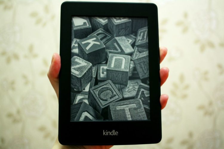 En la foto una mano sosteniendo un libro electrónico de Amazon, el Kindle